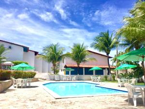a swimming pool with chairs and green umbrellas at Casa Praia dos Carneiros in Tamandaré