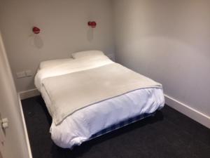 キングトンにあるThe Crossの小さな白いベッドが備わる客室です。