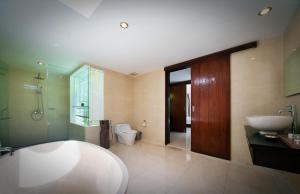 a bathroom with a tub and a sink and a toilet at Kebun Villas & Resort in Senggigi