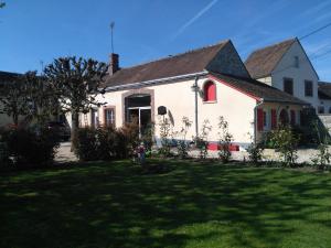 een wit huis met rode ramen en een tuin bij La cité des abeilles in Villemandeur