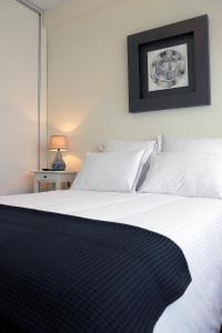 a bedroom with a large bed with white sheets at Porto Patricio Apartments in Porto