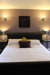 a bedroom with a large white bed with two lamps at Swan Motel in Beccles