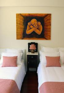 ポルトにあるPorto Patricio Apartmentsの壁に絵画が飾られた部屋のベッド2台