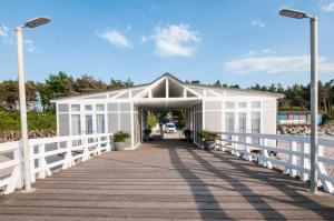 a white building on a pier next to the beach at Pokoje na plaży in Ustronie Morskie