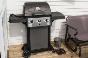 a bbq grill with a chair next to it at Mama`s By The Sea B&B in Clark's Harbour