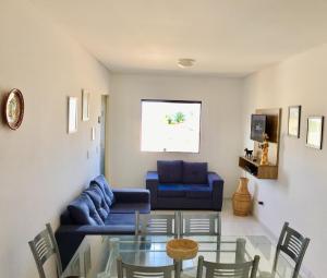 a living room with a blue couch and a glass table at Maragogi Praia Flats in Maragogi