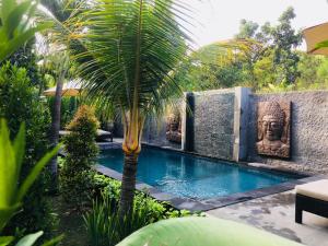 a swimming pool with a palm tree in a garden at Isola D'oro lembongan in Nusa Lembongan