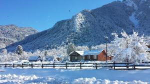 una casa cubierta de nieve frente a una montaña en Parque Amavida en Malalcahuello