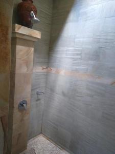 y baño con ducha y pared de piedra. en Apa Kabar Villas, en Amed
