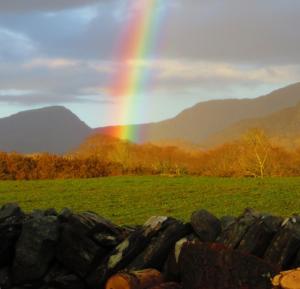 a rainbow over a field with a stone fence at Garth Engan Private Self Contained B&B with Garden Area in Llanbedr
