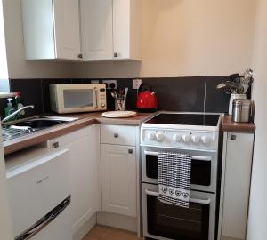 a kitchen with a stove and a microwave at The Beekeeper's Cottage in Saint Columb Major