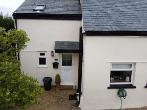 a white house with a black roof at The Beekeeper's Cottage in Saint Columb Major