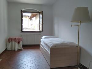 - une chambre avec un lit, une lampe et une fenêtre dans l'établissement La Corte del Conte, à Rovereto