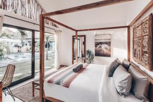 a bedroom with a bed and a large window at Beyond Bungalows in Canggu