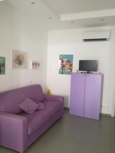 a purple couch in a living room with a tv at Lavanda in Marina di Ragusa