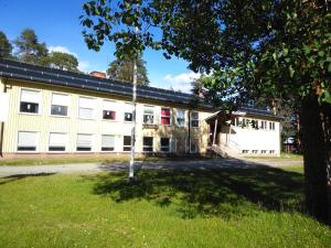 un grande edificio bianco con un albero in primo piano di Gafsele Lappland Hostel a Väster Gafsele