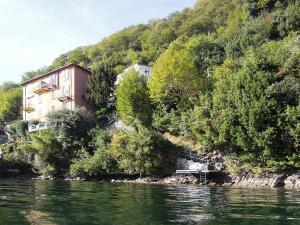 a building on the side of a river with trees at Charming house with the private dock I in Argegno