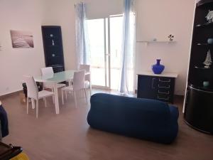 ポルト・エンペードクレにあるCasa Vacanze A Due Passi Dal Mareのリビングルーム(テーブル、椅子、青いソファ付)