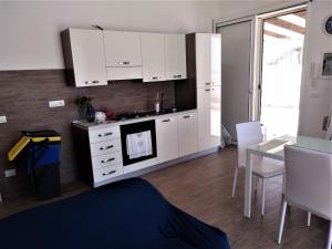 a kitchen with white cabinets and a table with chairs at Casa Vacanze A Due Passi Dal Mare in Porto Empedocle