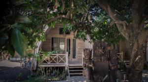 a statue in front of a house under a tree at Flowers & Fire Yoga Garden in Gili Air