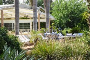 a patio with white chairs and palm trees at The White Chalet View in Moshav Ramot +8 photos