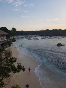 a person walking on a beach with boats in the water at Radiance Sunset Villas Lembongan in Nusa Lembongan