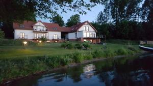 a large house on the side of a river at Siedlisko Kłodno in Sulęczyno