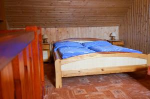 a bedroom with a bed with blue sheets and wooden walls at Apartmány Petronela in Hrabušice
