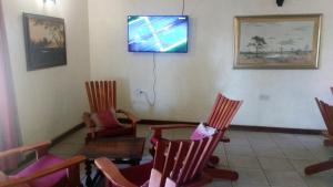 Zimmer mit Stühlen, einem Tisch und einem TV an der Wand in der Unterkunft Serowe Hotel in Serowe