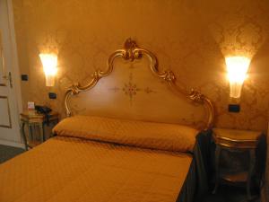 a bedroom with a bed with two lights on the wall at Hotel Belle Epoque in Venice