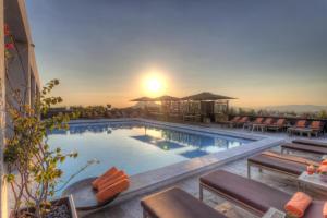 a swimming pool with a sunset in the background at President Hotel in Athens