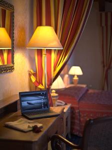 a laptop computer sitting on top of a bed next to a lamp at Hotel Orologio in Ferrara