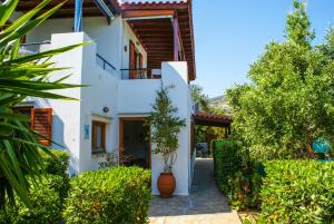 a white house with a courtyard and trees at Anemoesa in Batsi