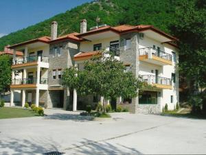 un gran edificio con un árbol delante en Hotel Galaxias en Kato Loutraki