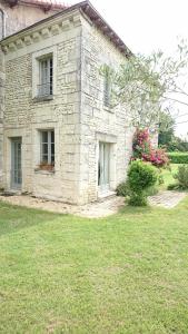L'Olivier في Monts-sur-Guesnes: منزل حجري مع نافذتين وساحة خضراء
