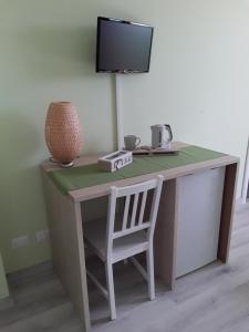 a desk with a chair and a television on a wall at Tra MENTA e MELIGA in Carignano
