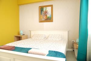 a bedroom with a white bed with a painting on the wall at City Home Timisoara in Timişoara