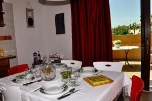 une table avec des assiettes et des verres blancs et un rideau rouge dans l'établissement Casa Duminicheddha, mare e relax in Gallura, à Bassacutena 22 autres photos