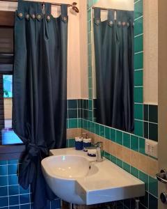 La salle de bains est pourvue d'un lavabo et d'un rideau de douche noir. dans l'établissement Casa Duminicheddha, mare e relax in Gallura, à Bassacutena