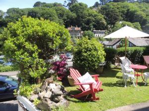 a yard with two red chairs and an umbrella at Orchard House Hotel in Lynmouth