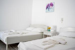 two beds in a white room with towels on them at Margo Antiparos in Antiparos