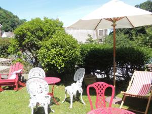 a group of chairs and tables with an umbrella at Orchard House Hotel in Lynmouth