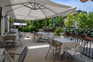 eine Terrasse mit Tischen, Stühlen und einem Sonnenschirm in der Unterkunft Hotel Le Boulevard in Lido di Venezia