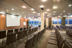 a conference room with chairs and a projection screen at Tulip Inn Turin West Rivoli in Rivoli