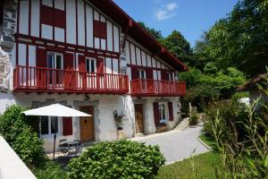 a white and red building with a balcony and an umbrella at studio Eder Enea in Cambo-les-Bains