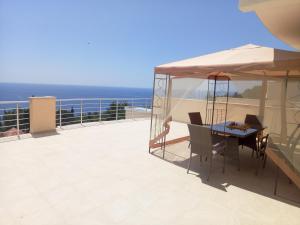 une table et des chaises sur un balcon avec l'océan dans l'établissement Villa Roan, à Bar
