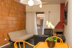 a living room with a couch and a table and chairs at Pousada Larimor in Boicucanga