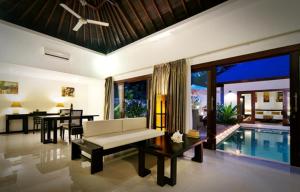 a living room with a couch and a table and a pool at Kebun Villas & Resort in Senggigi