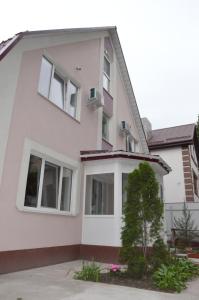 ein weißes Haus mit Fenstern und einem Baum in der Unterkunft Guest House Orchid in Kropywnyzkyj