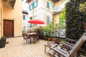patio z krzesłami i stołem z czerwonym parasolem w obiekcie Appartamenti Orta w mieście Orta San Giulio
